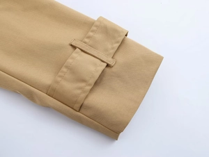 Detail of khaki trench coat cuff with adjustable strap and premium twill fabric texture
