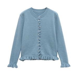Détail du cardigan en maille bleu clair avec boutons blancs et bords à volants