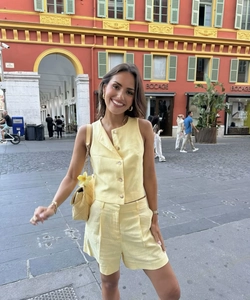 Detail eines hellgelben Leinenwesten-Sets mit Knöpfen und passenden Shorts mit hoher Taille