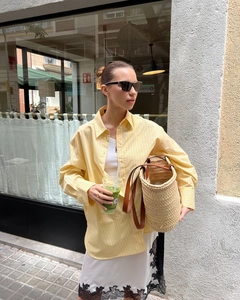 Detail of oversized yellow striped cotton shirt with relaxed long sleeves and poplin texture