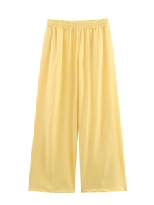 Detail of high waisted bright yellow wide leg trousers with elastic waist and flowing fabric