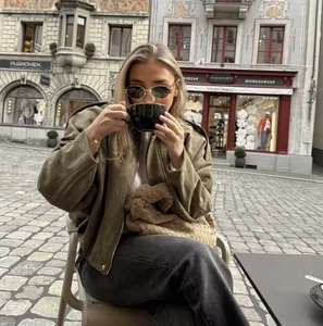 Street style shot of army green suede bomber jacket with large woven handbag and sunnies