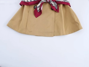 Detail of khaki trench skirt featuring a red striped scarf belt and dark button accents