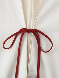 Detailed close-up of white cotton linen fabric with red cotton ribbon tie and soft lining