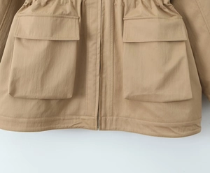 Detail of khaki utility jacket showing adjustable waist drawstring and large cargo pockets