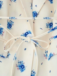 Detailansicht des Revers eines cremefarbenen Blazers mit blauem Blumenmuster und Bindeband