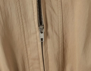 Detail of silver metal zipper and khaki nylon fabric texture on a trench coat