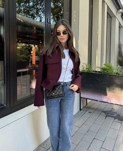 Detail of burgundy wool jacket with large pockets and black quilted chain handbag