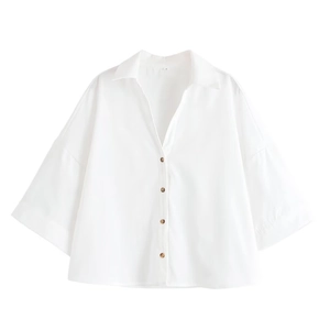 Détail du chemisier blanc à manches larges avec boutons aspect bois et col en V moderne