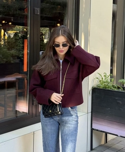 Detail of burgundy wool jacket featuring a silver zipper closure and large front pockets