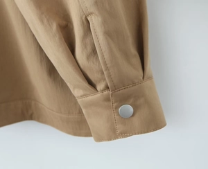 Detail of khaki cargo trench coat featuring silver metal snap buttons and double stitching