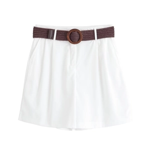 Détail d'un short blanc ample avec ceinture tressée marron et taille plissée