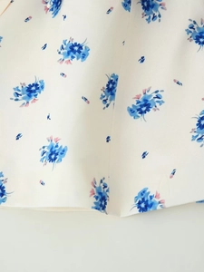 Detailaufnahme von cremefarbenem Stoff mit zartem blauem und rosa Blumendruckmuster