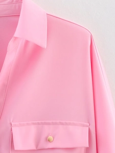 Macro shot of pink long-sleeved shirt showing twill fabric and gold round button detail