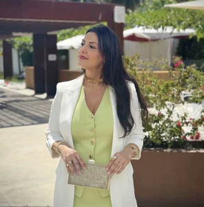 Detail view of the V-neck knit vest under a white blazer with elegant gold jewelry sets