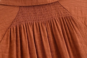Detailansicht von rostrotem Stoff mit Smok-Technik für elastische Textur und Struktur