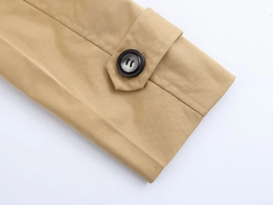 Close-up of khaki trench coat sleeve cuff with adjustable strap and marbled button detail