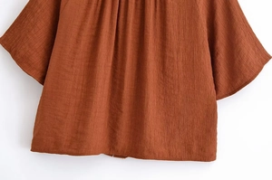 Detail der rotbraunen Textur mit Faltenkragen und weiten Fledermausärmeln für Damen