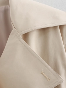 Close-up of high-quality stitching and buttonhole on beige double-breasted trench coat