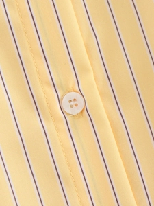 Detail of yellow and white striped poplin fabric with a pearl button and fine stitching