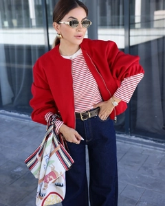 Close-up of a stylish red bomber jacket paired with a striped shirt and silk scarf detail