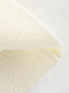 Macro shot of ivory knit fabric texture and high-density stitching on the V-neck vest