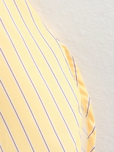 Detail of yellow and white striped poplin shirt with high-quality stitching and fabric texture