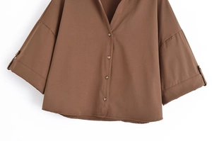 Détail d'une chemise marron ample avec manches larges, poignets boutonnés et un col en V