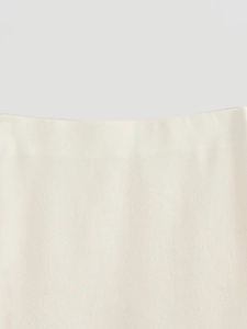 Close-up detail showing the fine texture and weave of the cream knit fabric vest and skirt