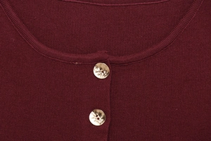 Detail of burgundy knit vest neckline with decorative gold hammered buttons