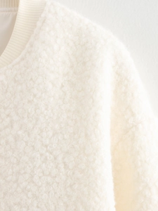 Gros plan sur la veste en polaire peluche blanc cassé avec col côtelé et texture douce