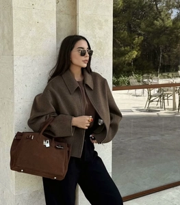 Dettaglio della giacca di lana marrone scuro con borsa in camoscio e occhiali da sole