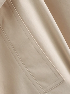 Detailed view of khaki trench coat showing professional double-stitch sewing and twill fabric