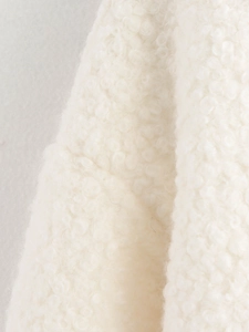 Gros plan sur le tissu imitation peau de mouton crème montrant la texture et les coutures