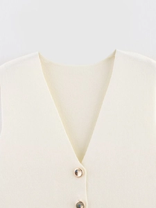 Detail of cream V-neck knit vest featuring textured fabric and gold trim round buttons
