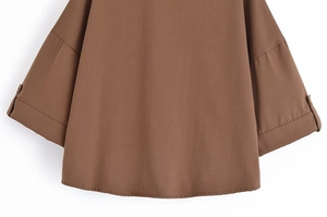 Vue détaillée de la chemise marron ample montrant les manches tombantes et poignets à boutons