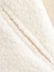 Gros plan sur un tissu bouclé en fausse fourrure blanc chaud pour vestes tendance
