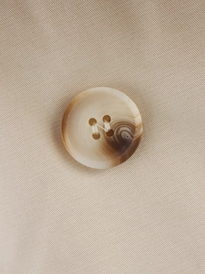 Macro shot of amber resin four-hole button on beige twill double-breasted coat