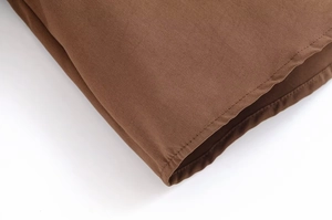Gros plan détaillé sur la texture du tissu marron et les coutures nettes du vêtement