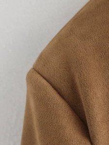 Close-up of premium brown suede blazer showing precise shoulder stitching and soft texture