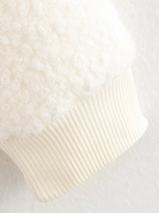 Détail des poignets côtelés et de la texture douce en peau de mouton beige de la veste