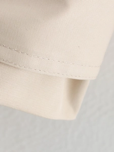Macro shot of precise double-stitched seams on beige twill trench coat fabric