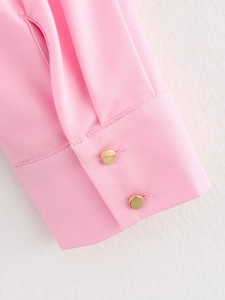 Detail of pink long-sleeve shirt cuffs with elegant golden buttons and twill texture