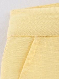 Detailansicht der gelben Shorts mit Seitentaschen und feinen Nähten aus Webstoff
