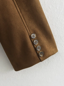 Detail of dark brown suede blazer sleeve featuring four amber textured decorative buttons