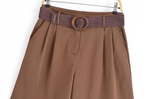 Détail du short camel taille haute avec plis et ceinture tressée marron avec boucle en bois
