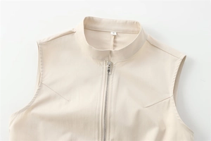 Detail of light beige stand collar top with silver metal zipper and precise stitching