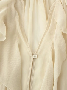 Macro-opname van V-hals roezeldetails en geplooide textuur op een crèmekleurige blouse
