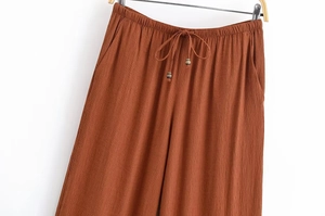 Detail der karamellfarbenen Hose mit elastischem Bund und Tunnelzug mit Holzperlen
