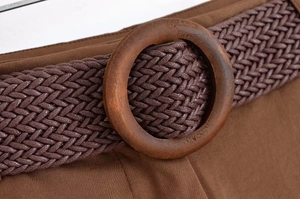 Détail de la ceinture tressée marron avec boucle en bois ronde sur tissu assorti